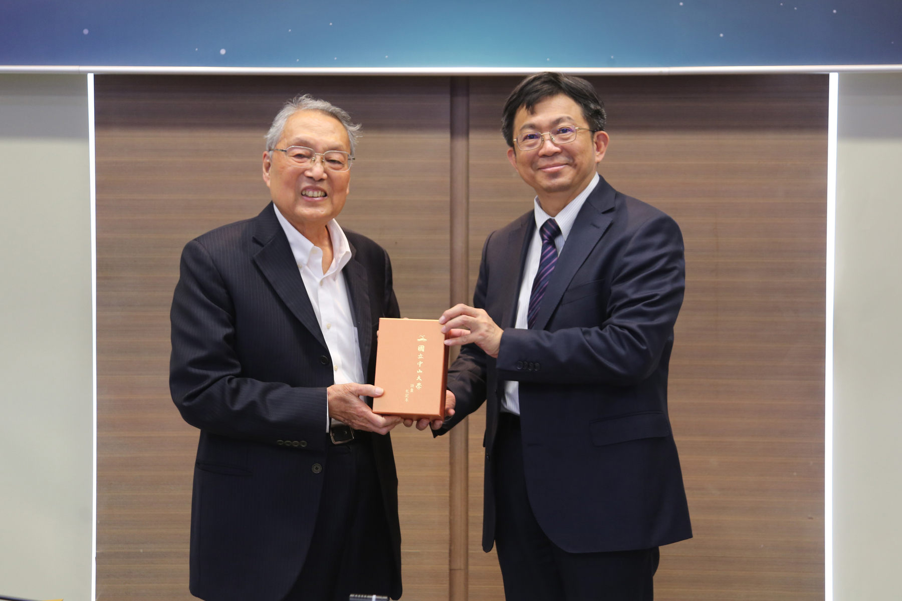 NSYSU President Chih-Peng Li (right) presents a limited-edition notebook of poems and sketches by the late NSYSU Emeritus Professor Kwang-Chung Yu to TICA Chairman Stan Shih.Image