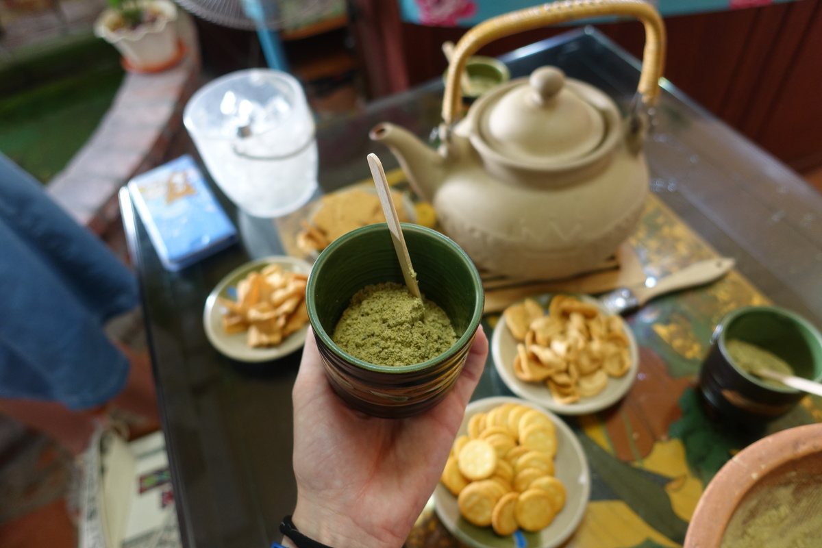 The seeds, nuts, and grain were ground manually in a clay pot with a wooden stick from the guava tree and then mixed with hot water; the lei cha is then served with cookies.