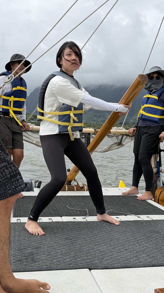 A student works with the hoe uli (steering paddle) aboard the double-hulled voyaging canoe Kānehūnāmoku.Image