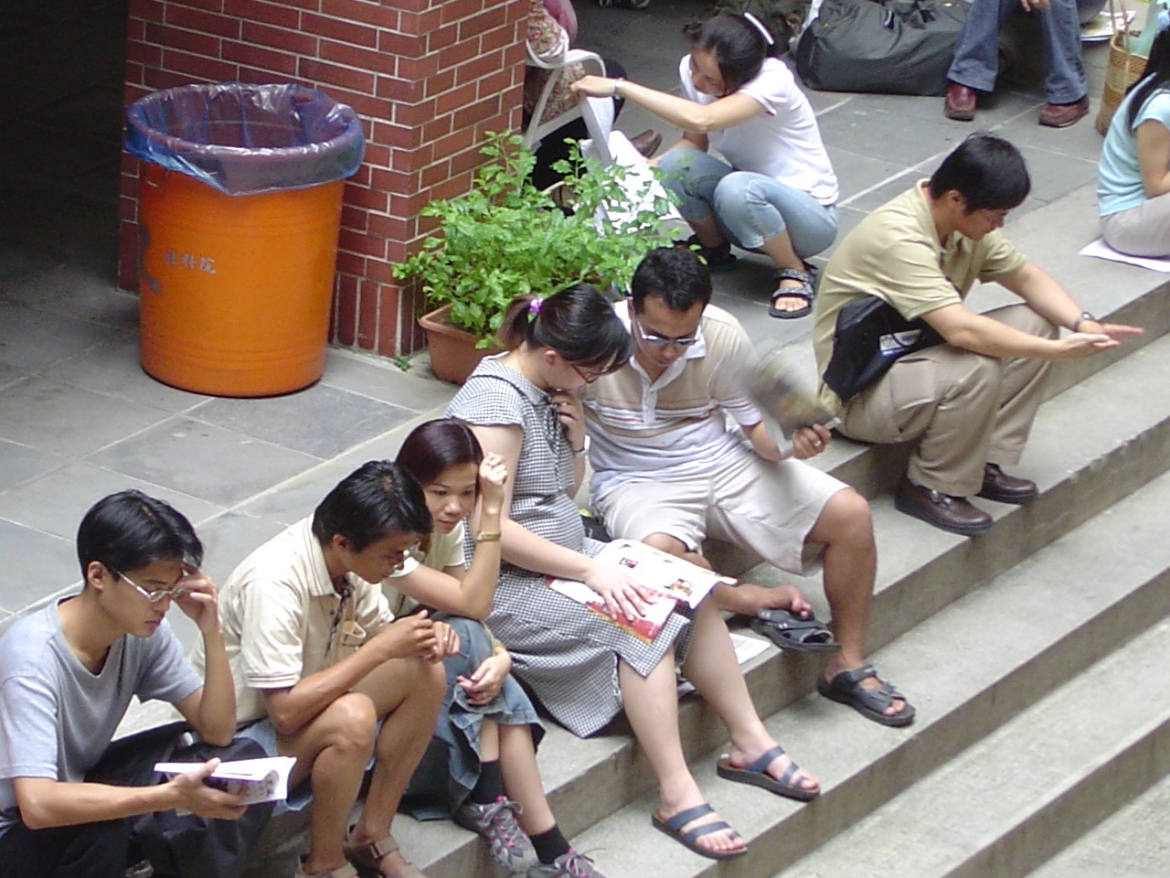 一位孕婦考生趁休息時候再多K點書,貼心的先生在一旁忙著為她搧風解熱.圖片