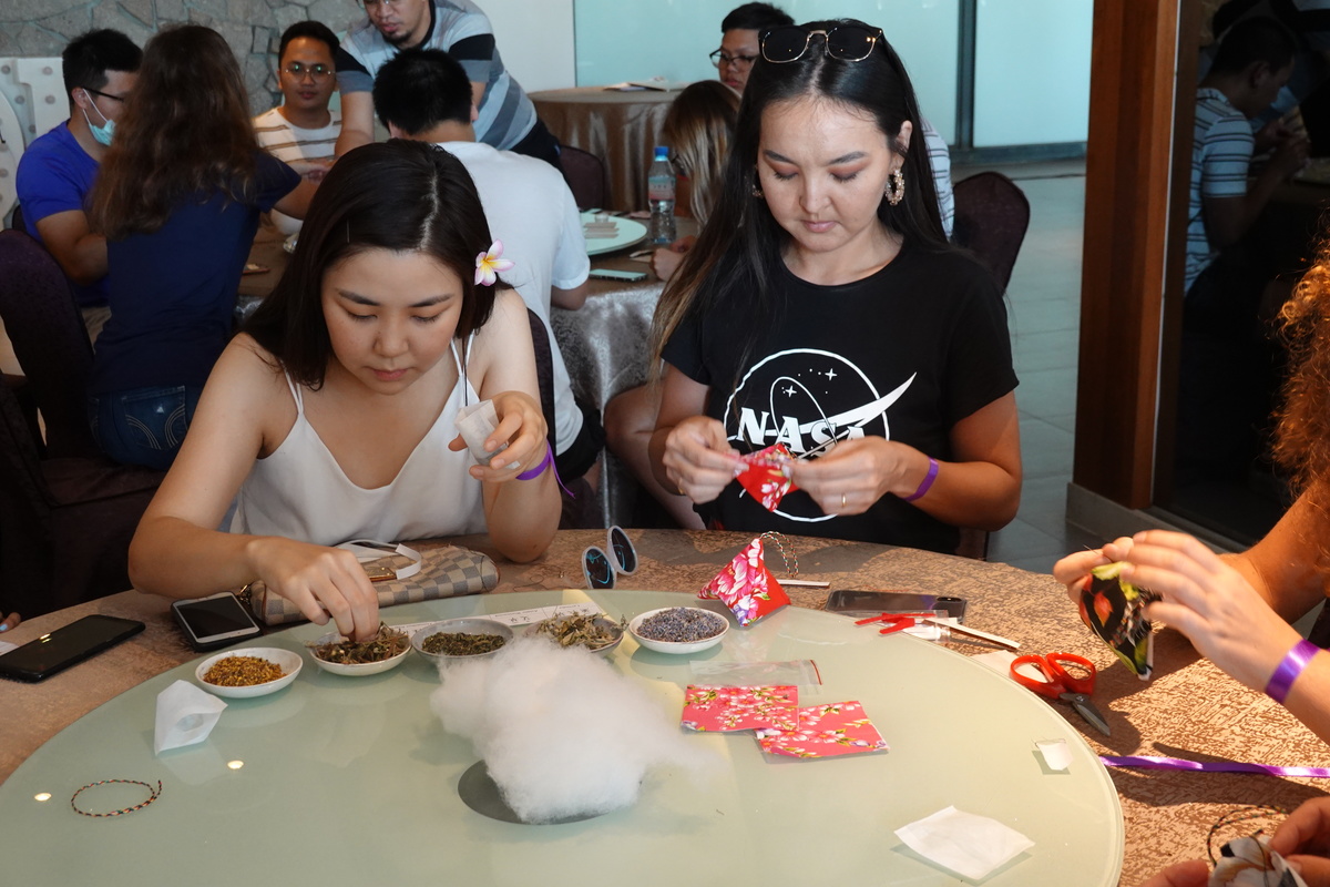 International students concentrating on sewing the traditional Hakka floral cloth and stuffing the sachets with dried herbs.
