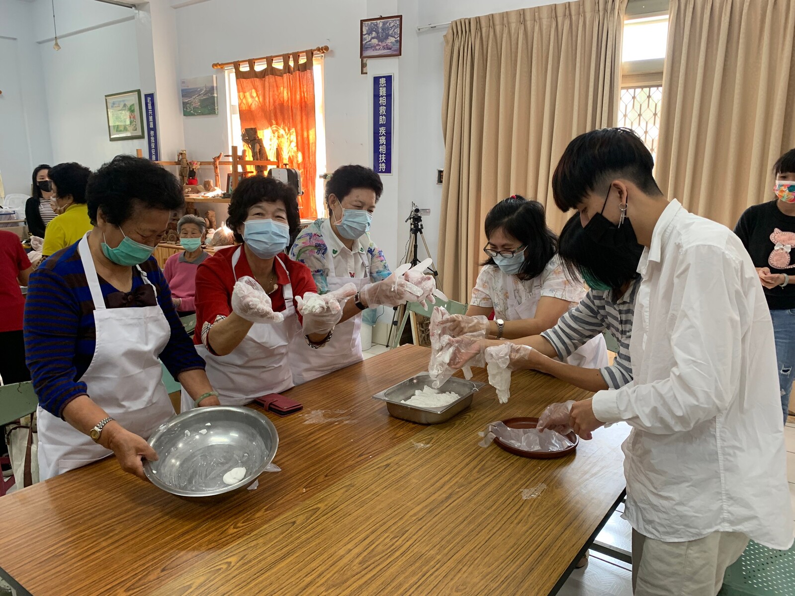Students of the Institute of Public Affairs Management wrapping mochi together with community elders.
