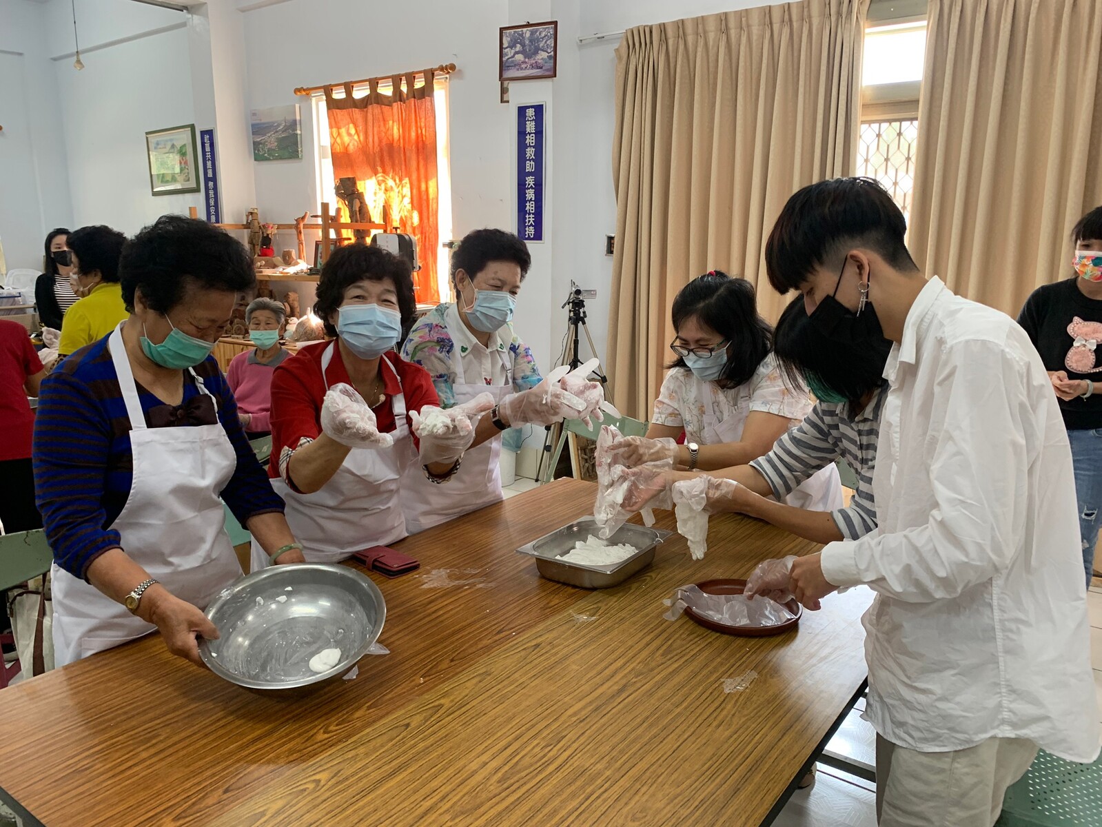 Students of the Institute of Public Affairs Management wrapping mochi together with community elders.Image