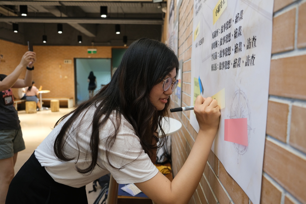Students signing blueprints during exhibitionImage