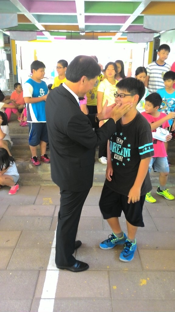 張鴻熙理事長親自幫受贈孩童戴眼鏡圖片