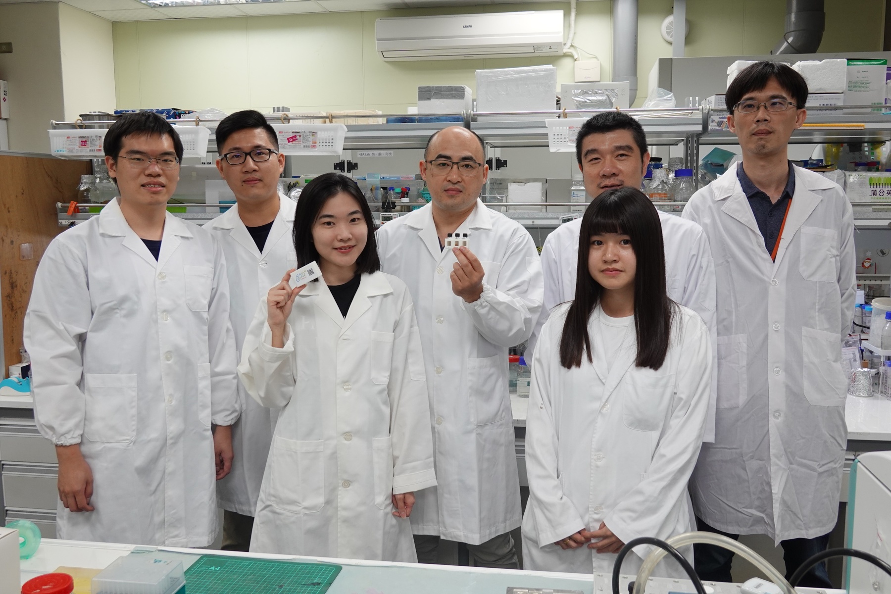 The team of Associate Professor Hung-Wei Yang (fourth on the left) of the Institute of Medical Science and Technology developed the ultra-sensitive measurement flask (EasyVial) and collaborated with the KMU team on a clinical trial with blind test verification that proved the high sensitivity of the developed technology that allows the detection of antibodies even in asymptomatic patients in an early stage of infection.