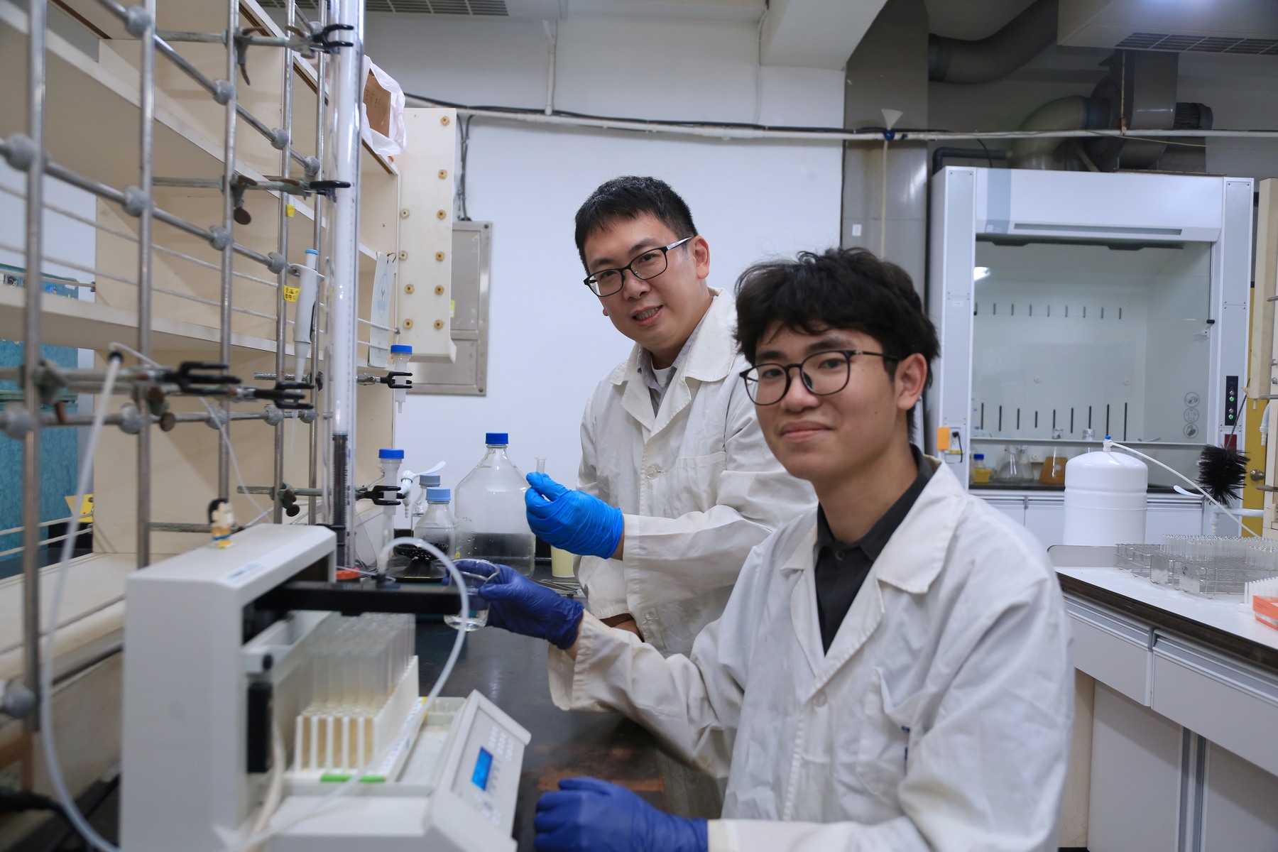 I-Ming Lee (back), Assistant Professor from the Department of Marine Biotechnology and Resources at NSYSU, instructs Master's student Sheng-Yen Luo (front) on operating a chromatography column analyzer.Image
