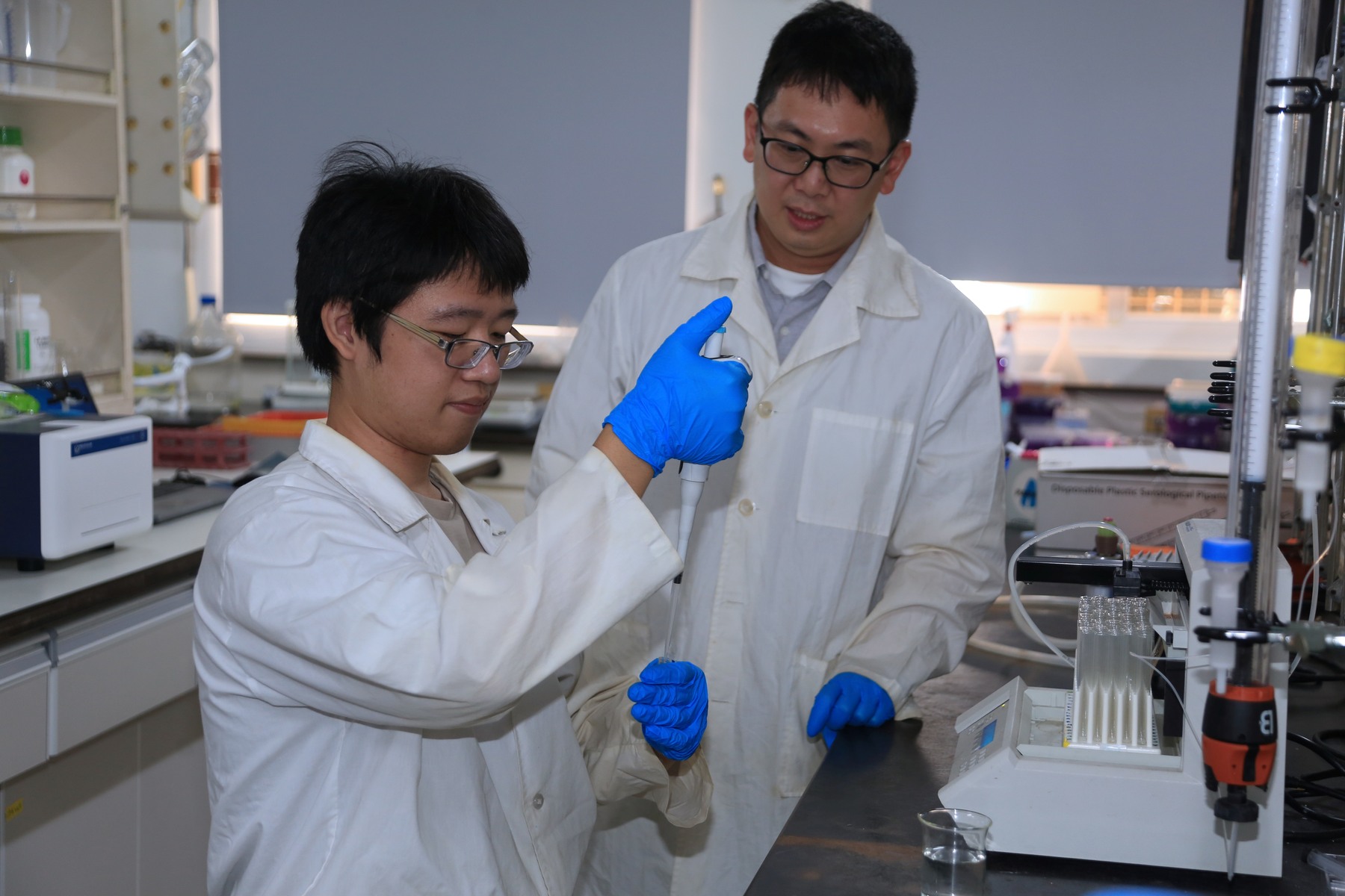 I-Ming Lee (back), Assistant Professor from the Department of Marine Biotechnology and Resources at NSYSU, instructs Master's student Kuan-Yu Liang (front) on injecting the extract into a test tube.Image